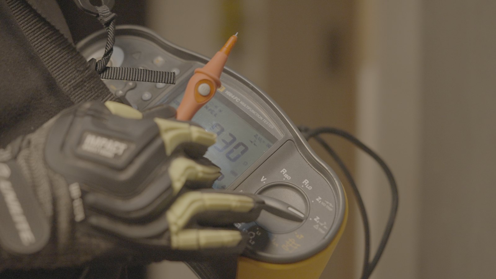 An electrician using a multifunction installation tester to verify a circuit